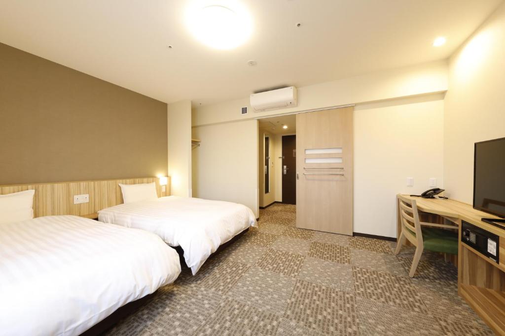 Postel nebo postele na pokoji v ubytování Dormy Inn Maebashi