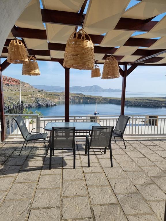 a patio with a table and chairs and a view of the water at Soultana studios in Líndos