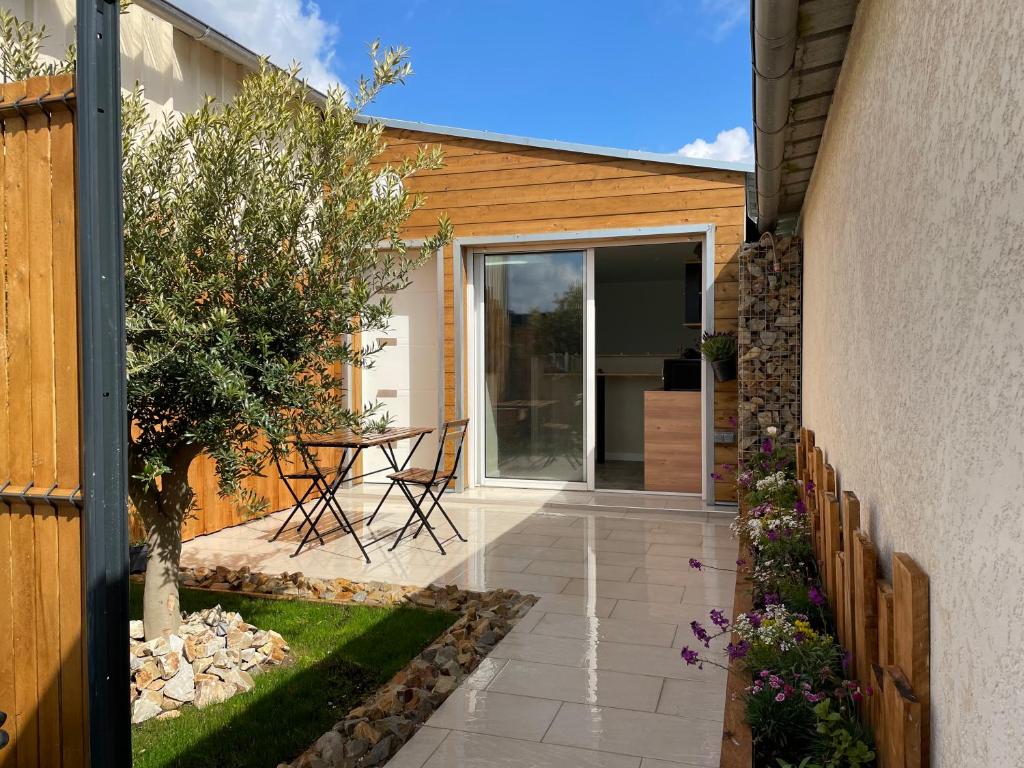 a garden with a patio with a table and chairs at Le Studio de l'Olivier in Courcelles-sur-Seine