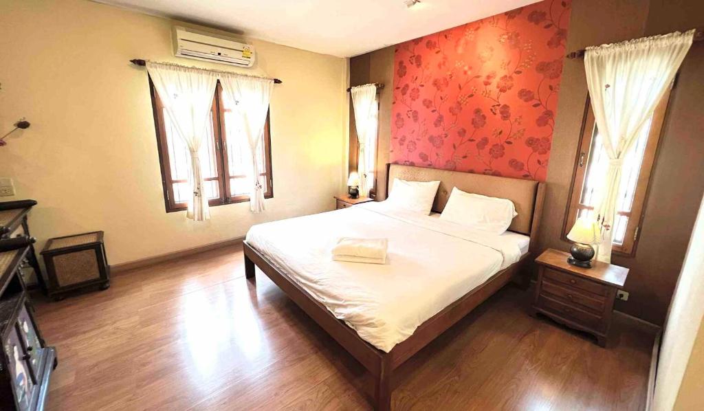 una camera da letto con un letto con lenzuola bianche e una parete rossa di Plumeriahome near Walking Street a Chiang Mai