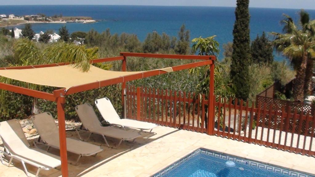 a pool with chairs and a umbrella next to a fence at Pomos Harbourbiew Villa in Pomos