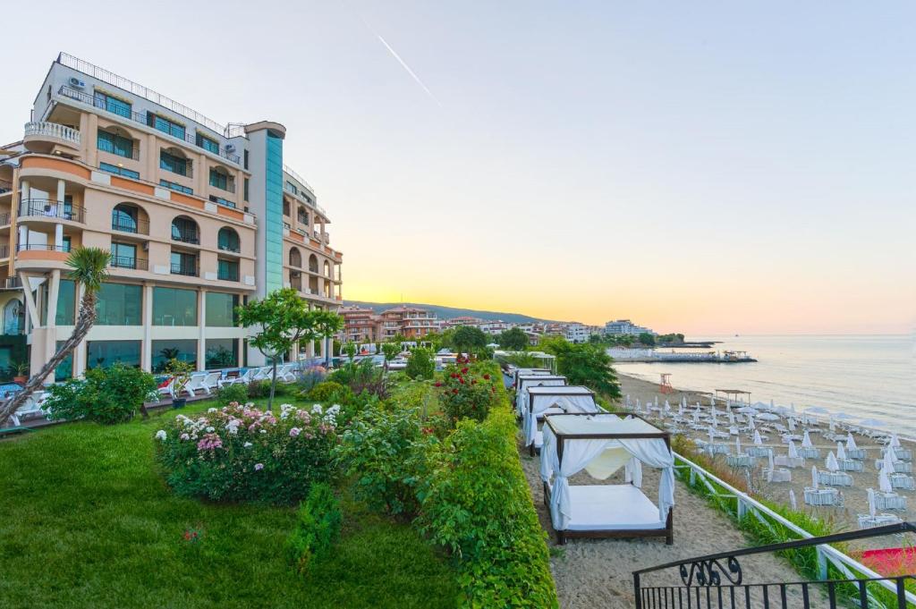 a hotel with a row of tables and chairs next to the water at Grand Hotel Sveti Vlas in Sveti Vlas