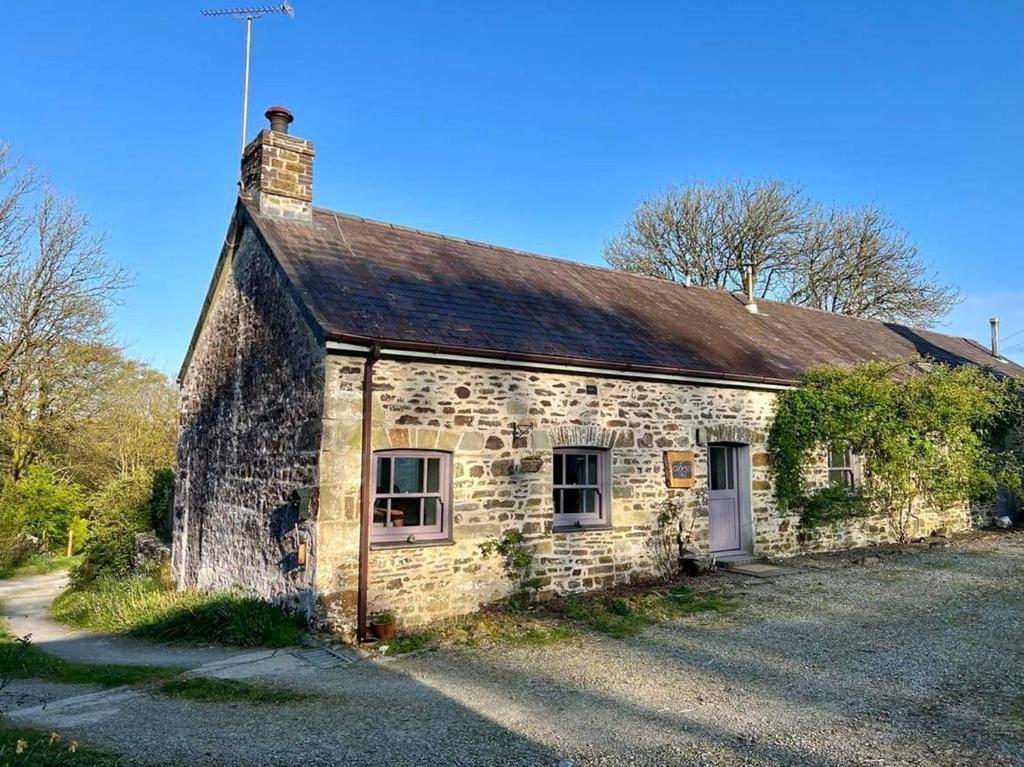 uma velha casa de pedra sentada numa estrada de terra em The Rose Barn, Ysgubor y Rhosyn em Llandysul