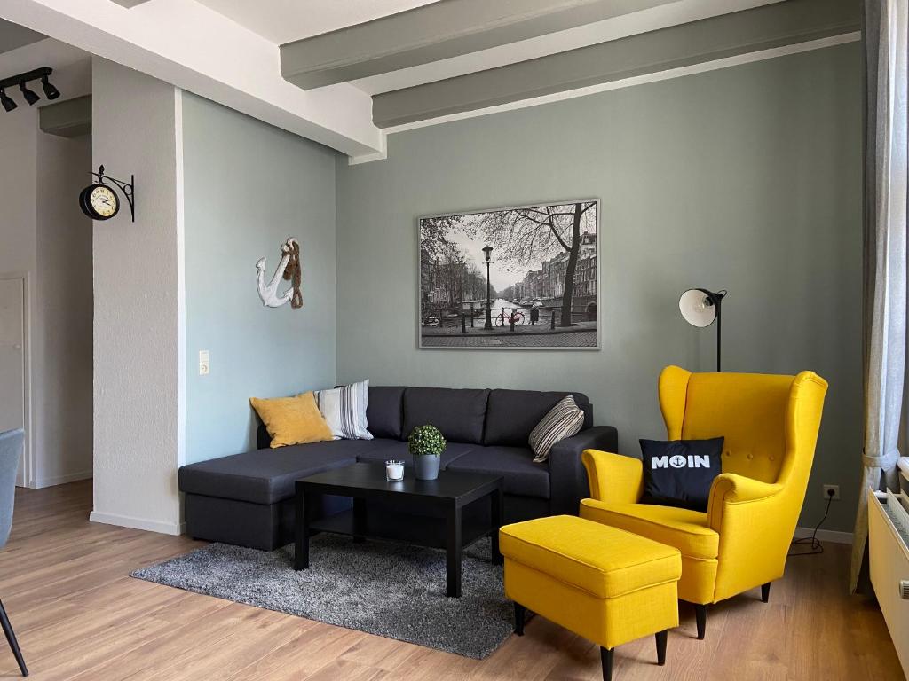 - un salon avec un canapé noir et des fauteuils jaunes dans l'établissement Ferienwohnung Hafensicht 25507, à Weener