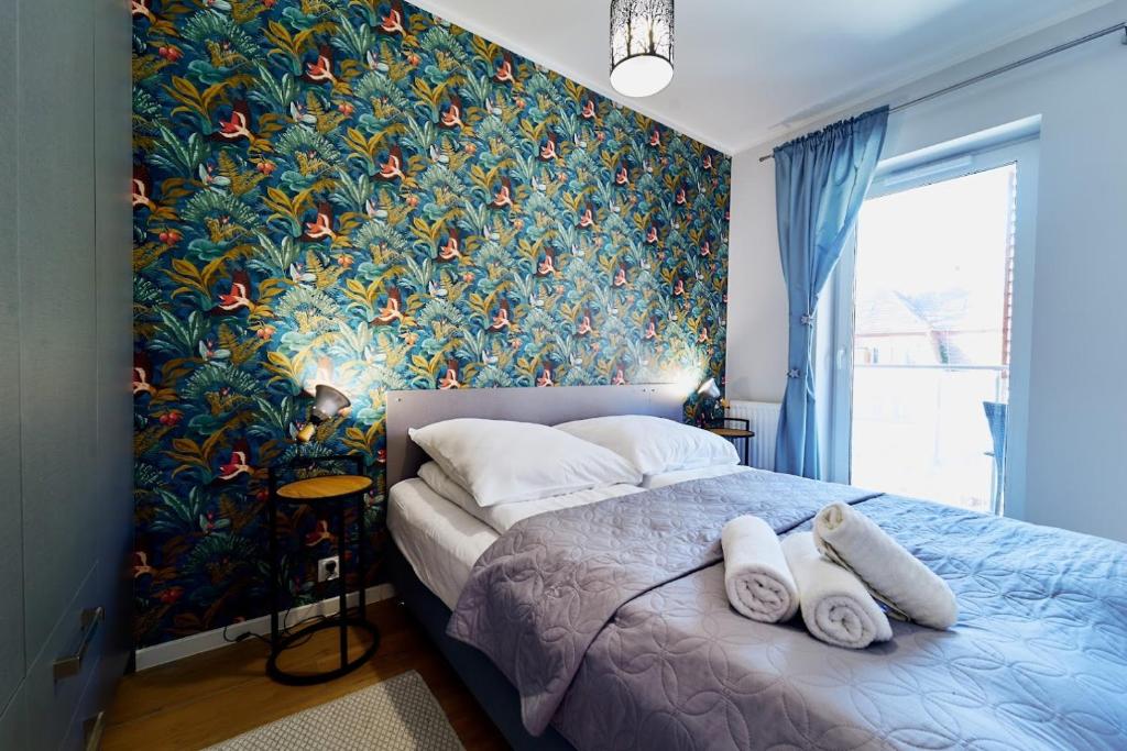 1 dormitorio con 1 cama grande y papel pintado con motivos florales en LAGUNA Apartament Polanica Residence 38, en Polanica-Zdrój