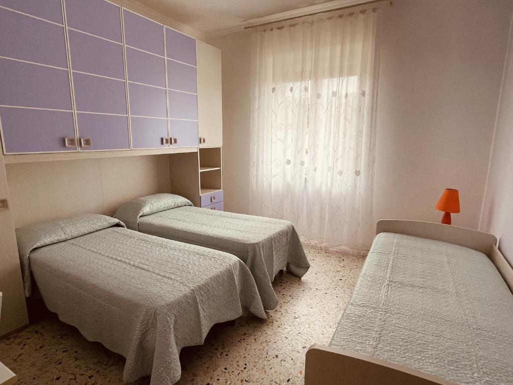 um quarto com três camas e uma janela em Nausicaa Beach and Town em Agropoli