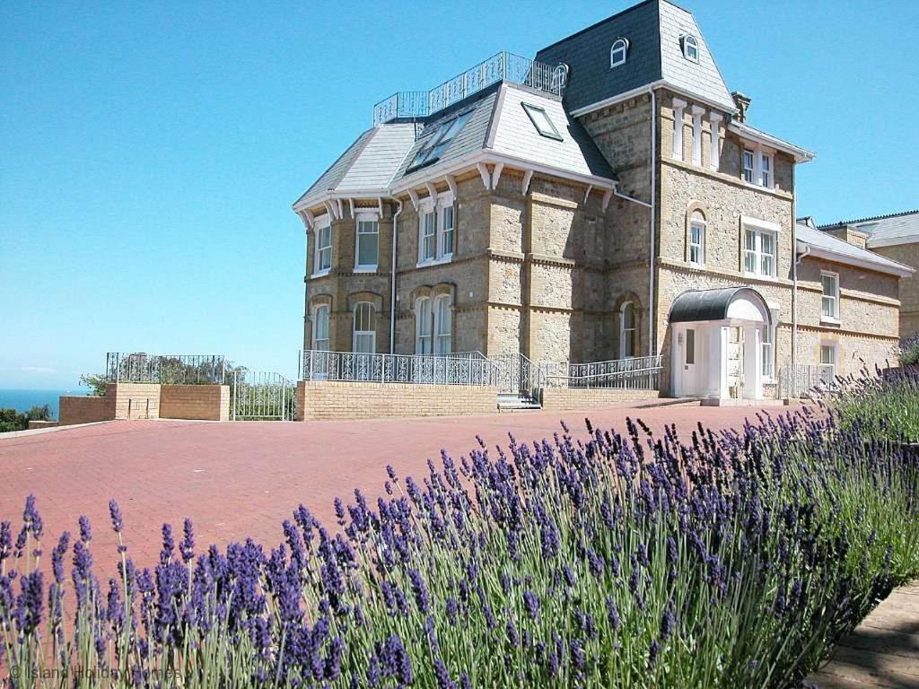 a large building with a tower on top of a field of purple flowers at Sea View in Shanklin