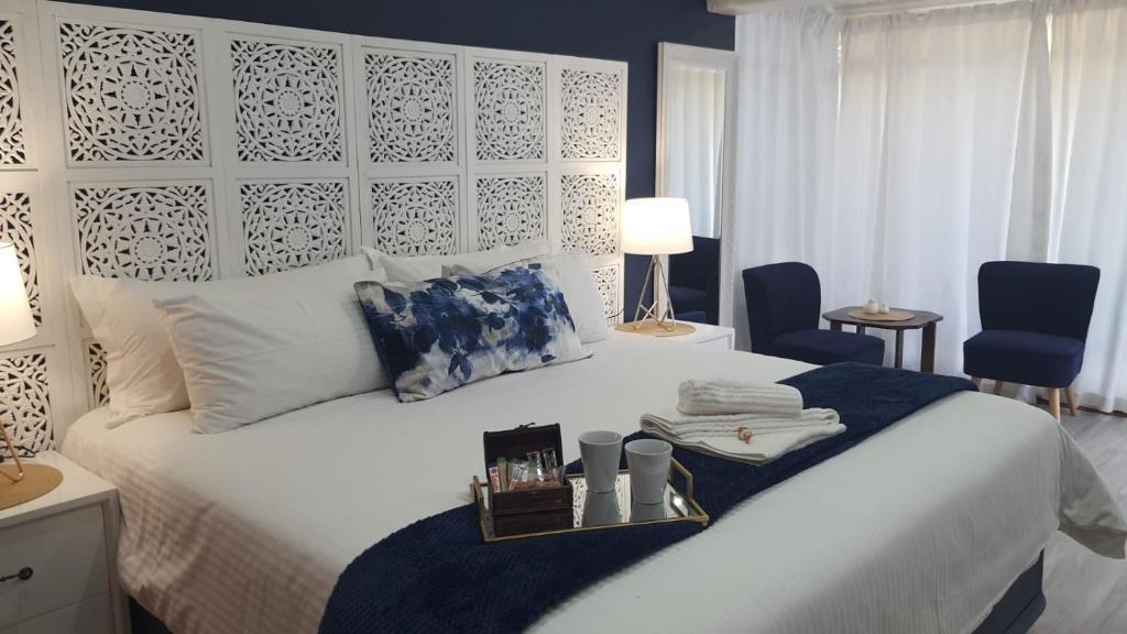 1 dormitorio con 1 cama blanca grande con manta azul en Gemstone Guest House en Klerksdorp