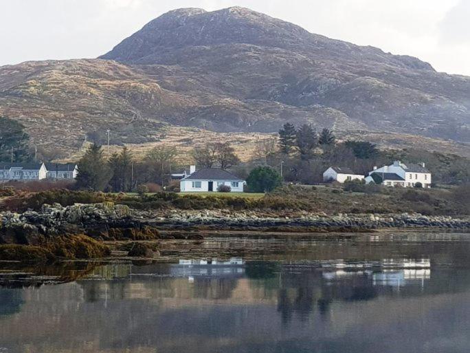 een dorp met huizen en water met een berg bij Waterside Cottage, Cashel in Galway