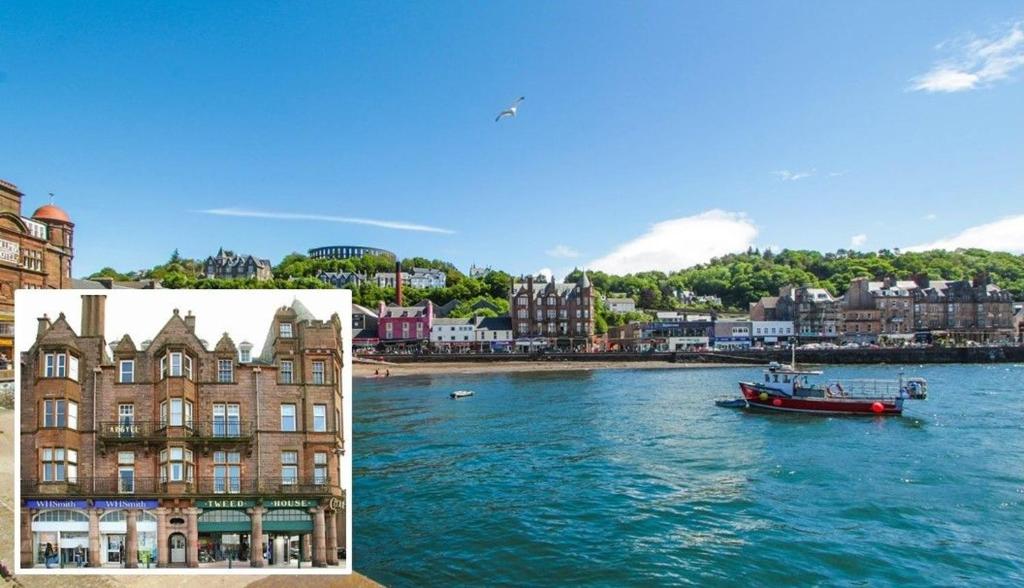 een boot in het water naast een gebouw bij Argyll Mansions in Oban