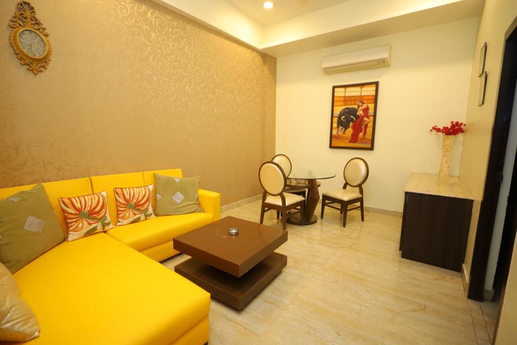a living room with a yellow couch and a table at JM Vistaraa in Bareilly