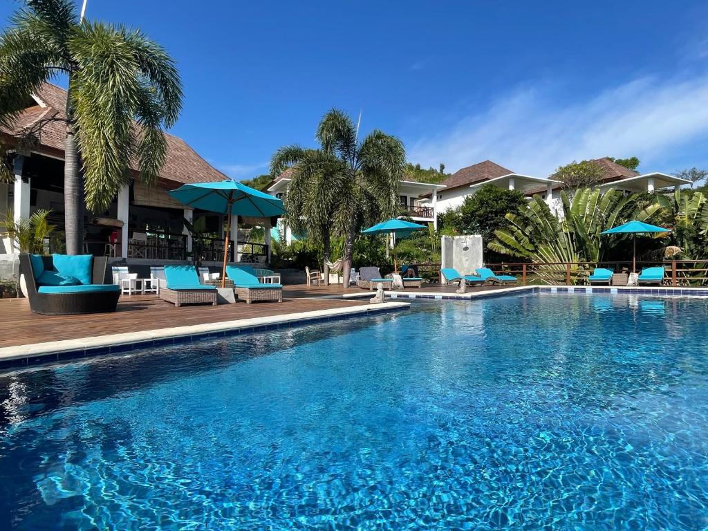 a large swimming pool with blue chairs and umbrellas at The Endless Summer Resort in Bumbang