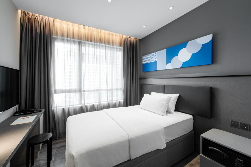 a bedroom with a bed and a desk and a window at Komune Living in Kuala Lumpur
