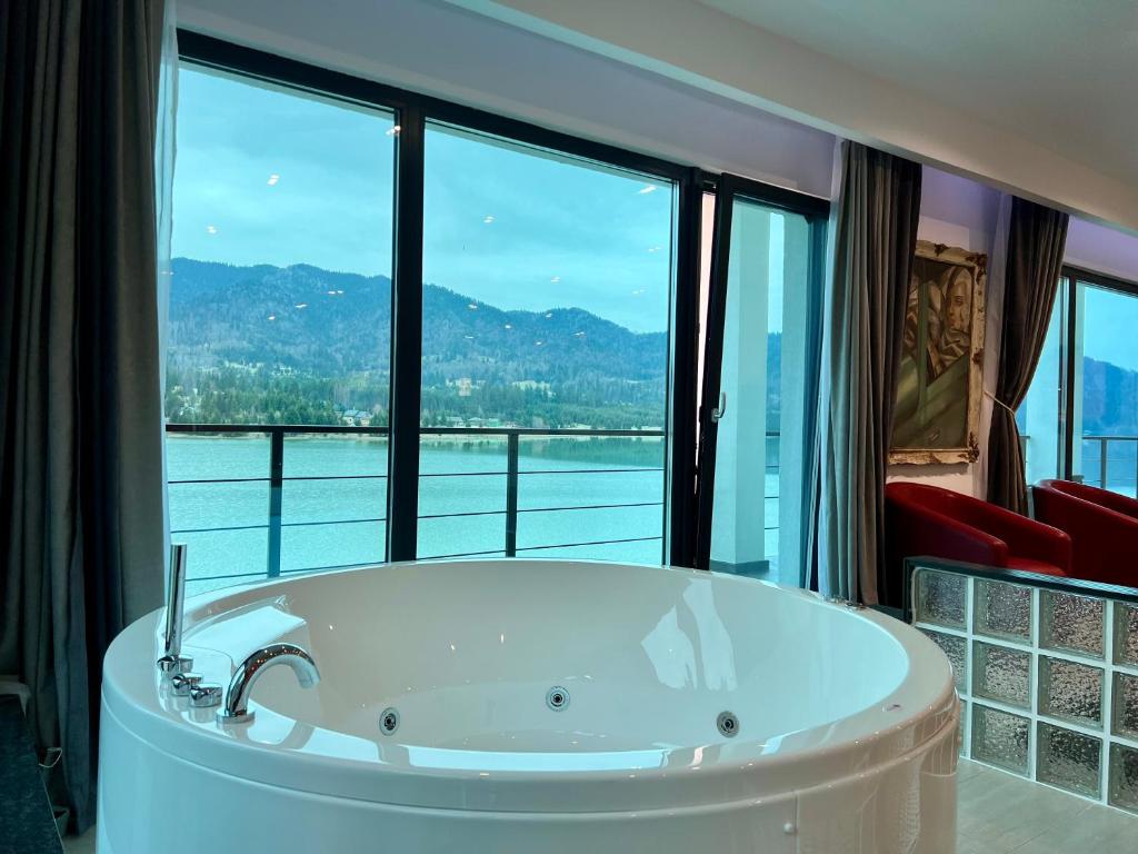 a bath tub in a room with a large window at Casa Eden - Apartamente langa lac in Colibiţa