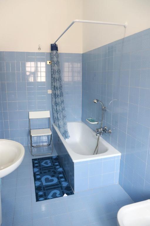 W wyłożonej niebieskimi kafelkami łazience znajduje się wanna i umywalka. w obiekcie B&B LA CASA DEI FIORI w mieście Amorosi