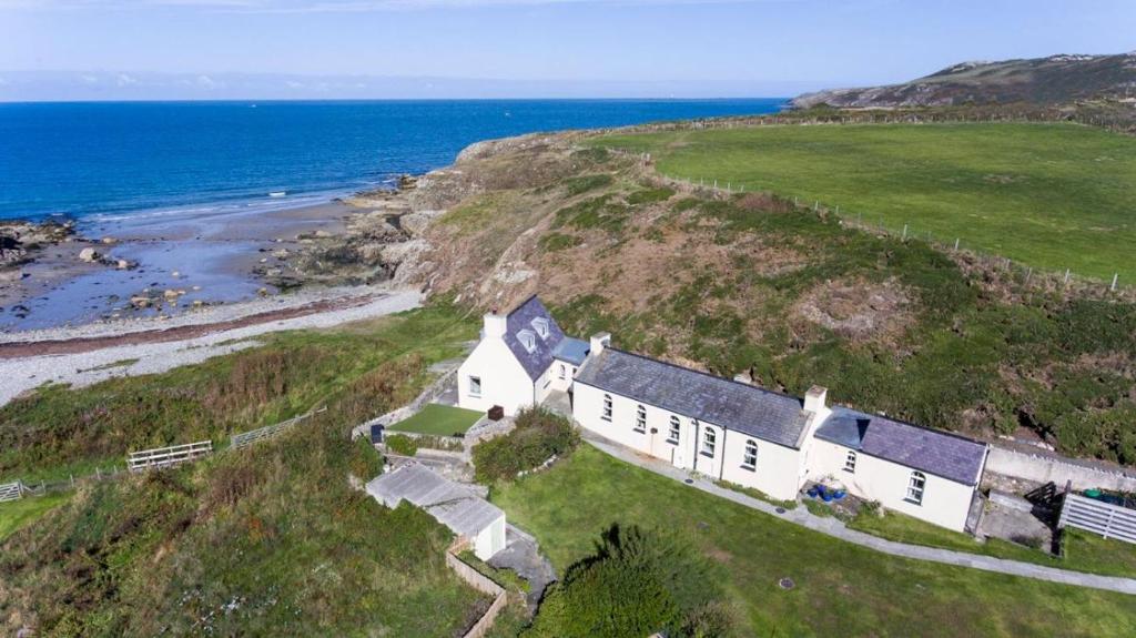 an aerial view of a house on a hill next to the ocean at Cable Cottage in Llanrhyddlad
