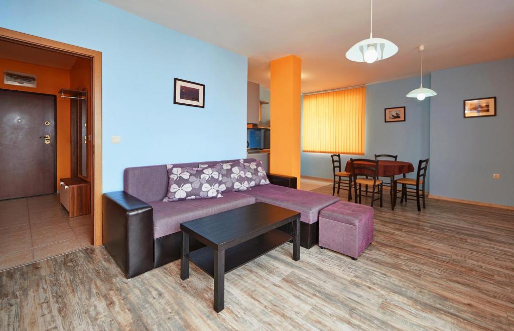 sala de estar con sofá púrpura y mesa en Apartments Dimitrovi, en Pomorie