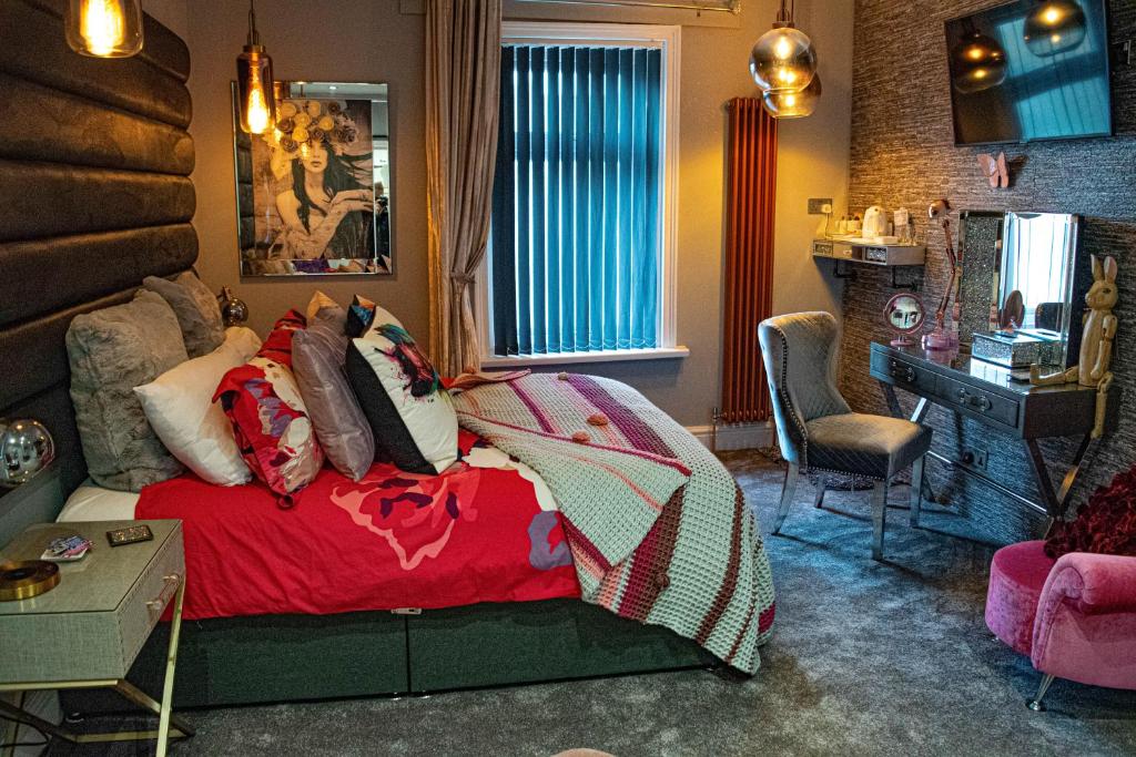a room with a bed, a chair, a table and a lamp at The Arthington in Blackpool