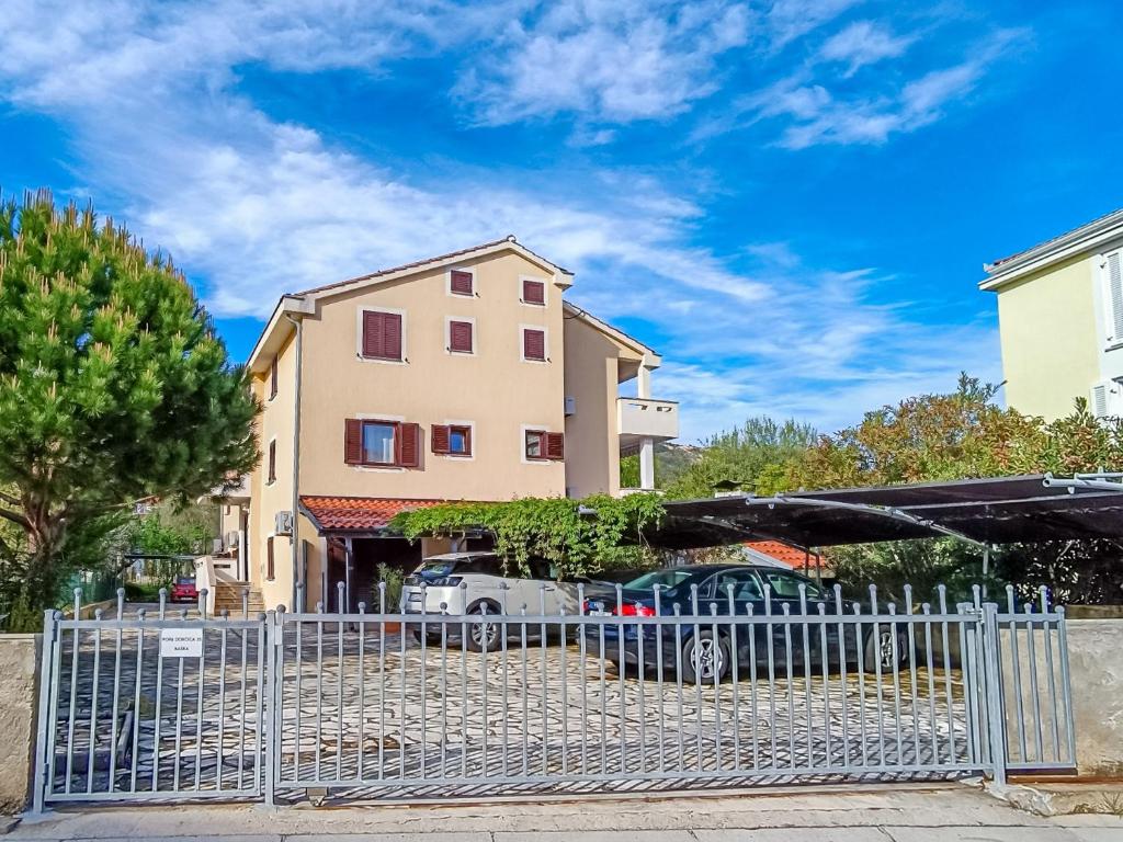 ein Gebäude mit Autos, die vor einem Zaun geparkt sind in der Unterkunft Marina in Baška