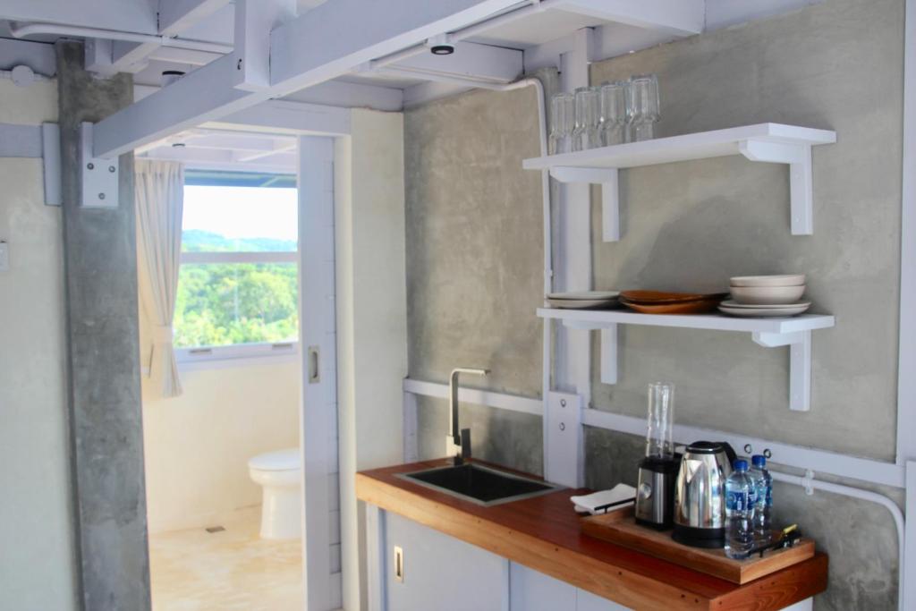 une cuisine avec des étagères blanches et un évier dans l'établissement Uluwatu Penthouse, à Uluwatu