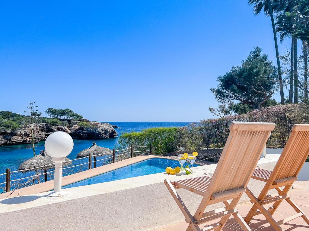 two chairs and a swimming pool with a view of the ocean at Villa Guacarachas in Cacla D'or
