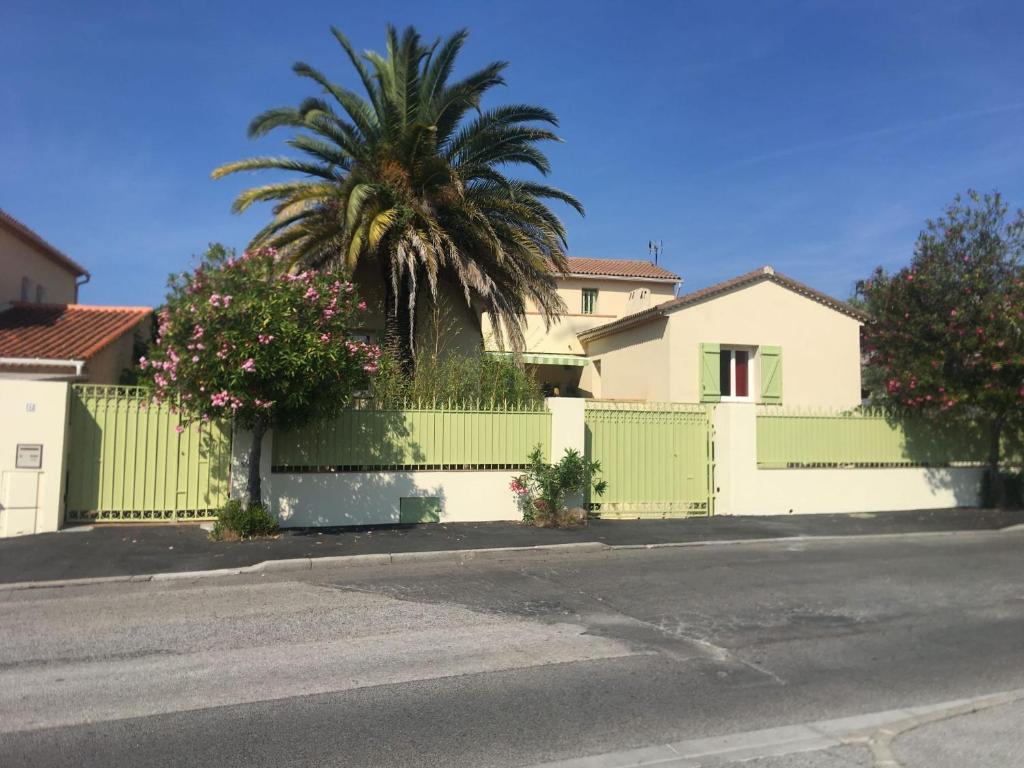 une clôture blanche avec un palmier devant une maison dans l'établissement Le gîte des Palmiers, à Hyères