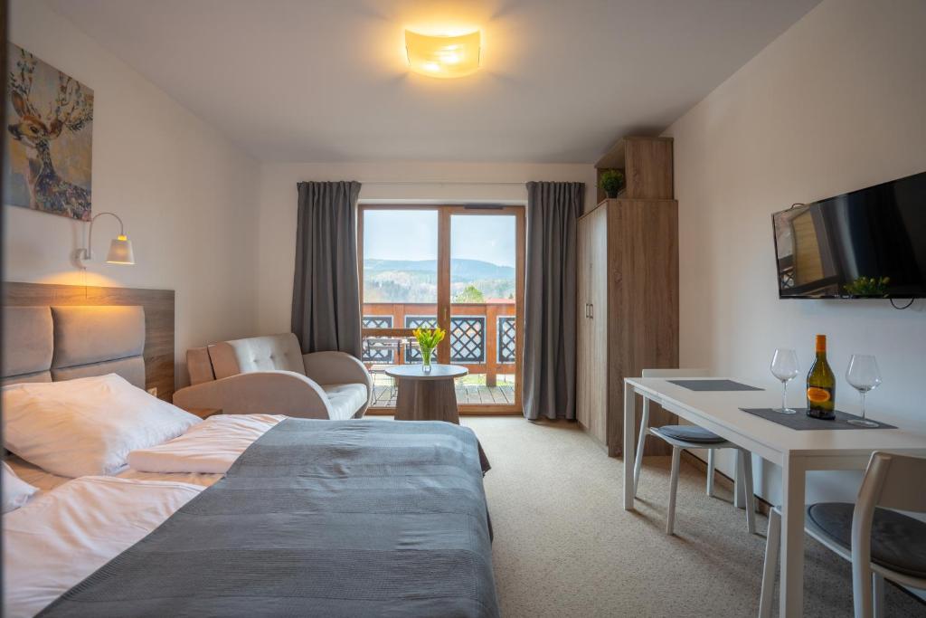 a hotel room with a bed and a table and a balcony at RentPlanet - Apartamenty Okrzei in Szklarska Poręba