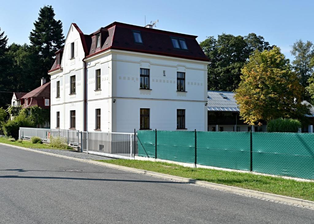 a white house with a fence next to a street at Villa vitality in Osečná