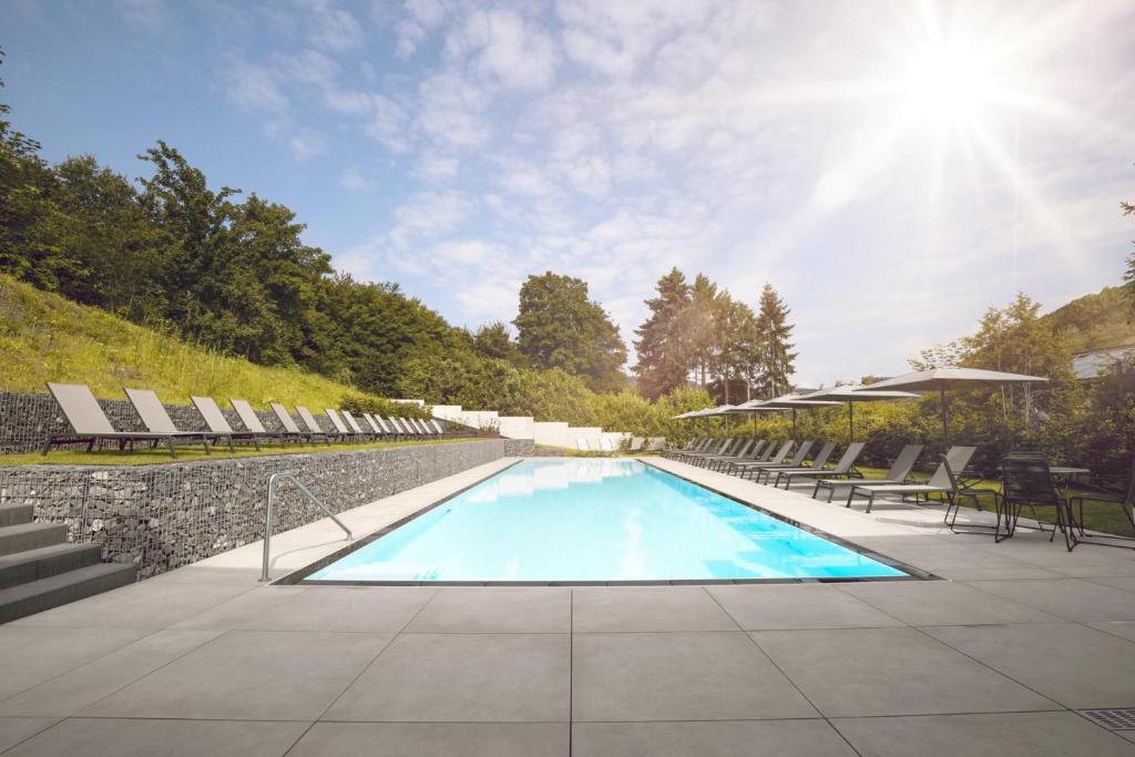einen Pool mit Stühlen und Sonne in der Unterkunft Hotel Halfenstube & Villa Spa 1894 in Senheim