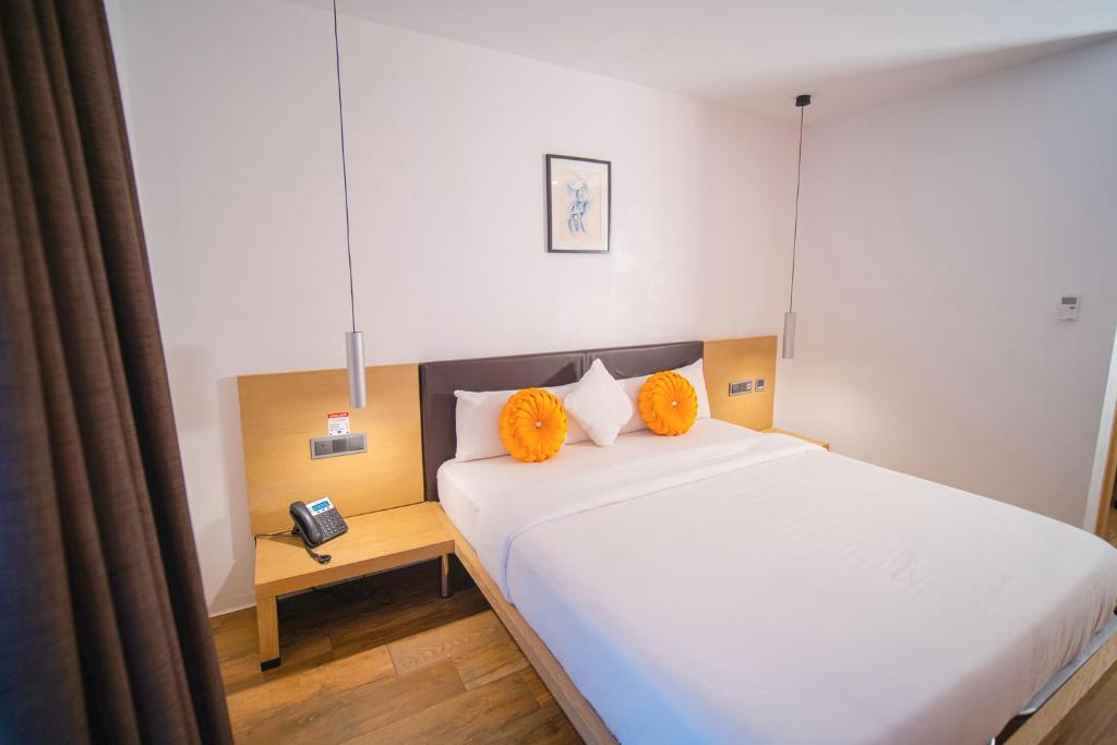 1 dormitorio con 1 cama con almohadas de color naranja y teléfono en SV Chrome, en Abuja