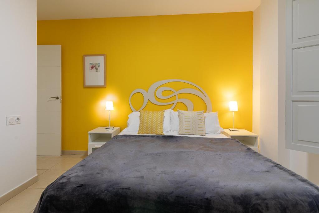 a bedroom with a large bed with a yellow wall at Reservaloen Plaza del Salvador in Seville