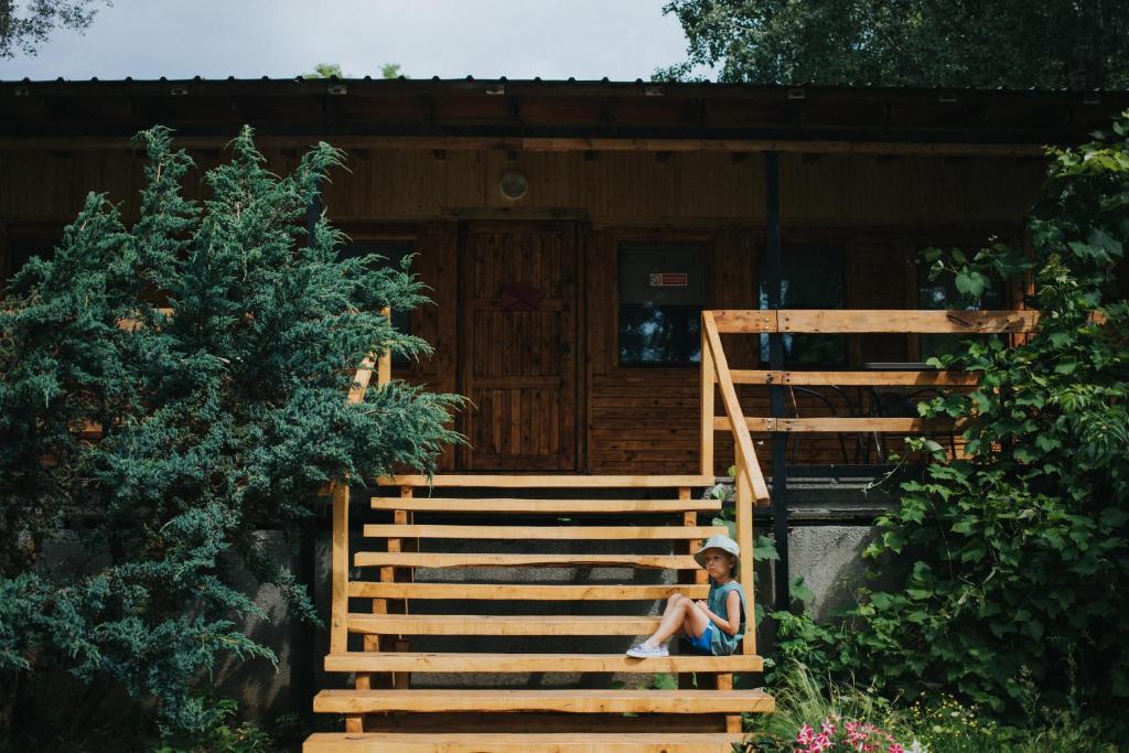 a young child sitting on the stairs of a cabin at Weź tu Przystań - Mikołajek 1 in Pomiechówek