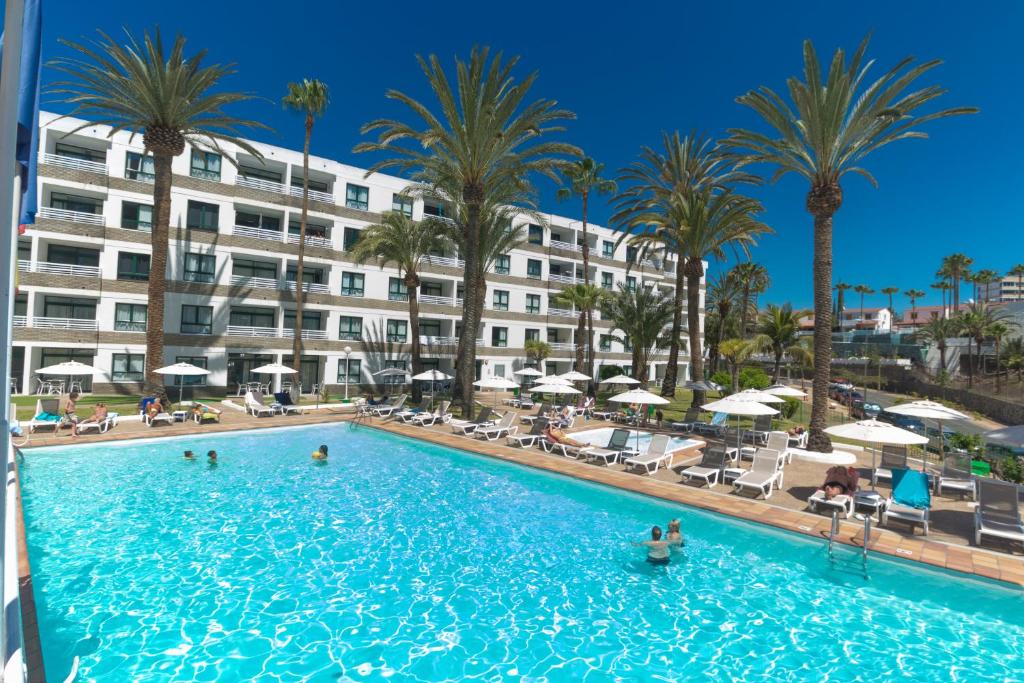 a swimming pool with palm trees and a building at Alsol Walhalla in Playa del Ingles