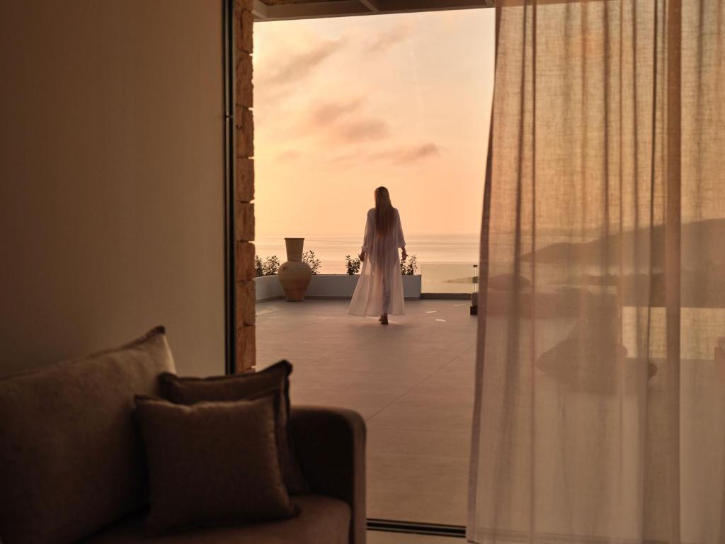 a woman in a white dress walking through a doorway at The Sall Suites Complex A - Iconic Sea Views, by ZanteWize in Agios Nikolaos