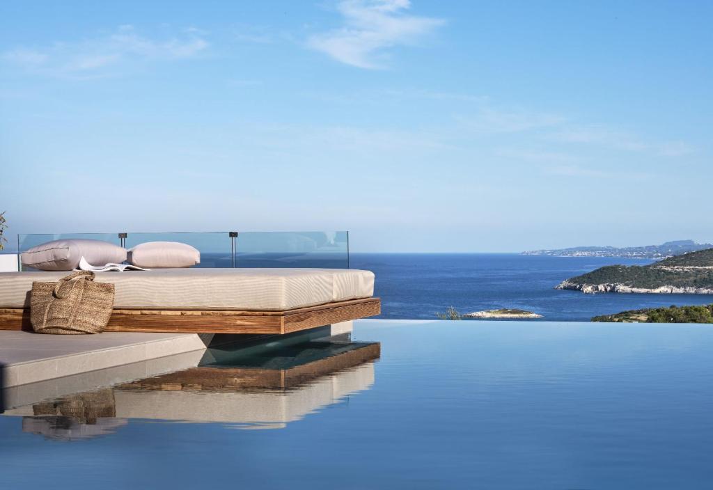 a bed on the edge of a pool with the ocean at The Sall Suites Complex A - Iconic Sea Views, by ZanteWize in Agios Nikolaos