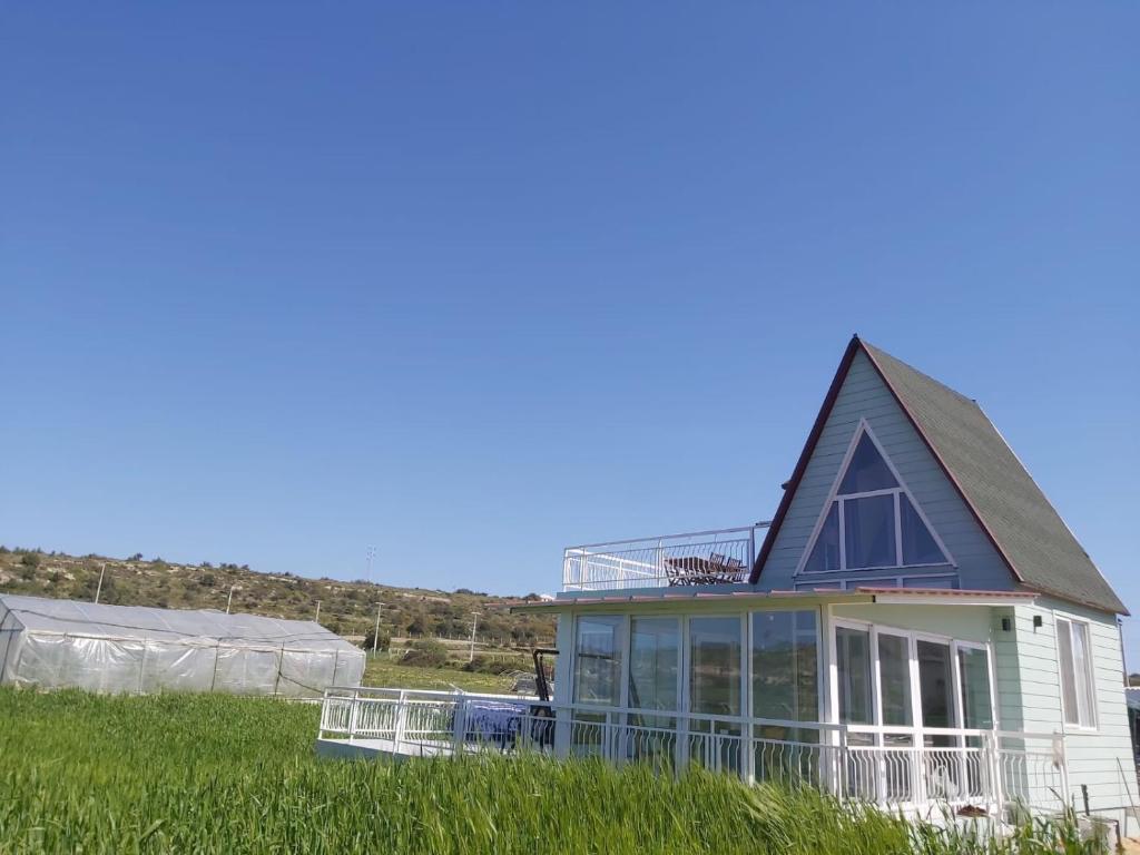 a house with a gambrel roof on top of a field at DENİZE 5 DAKİKA VE DOĞA EVİ in Cesme