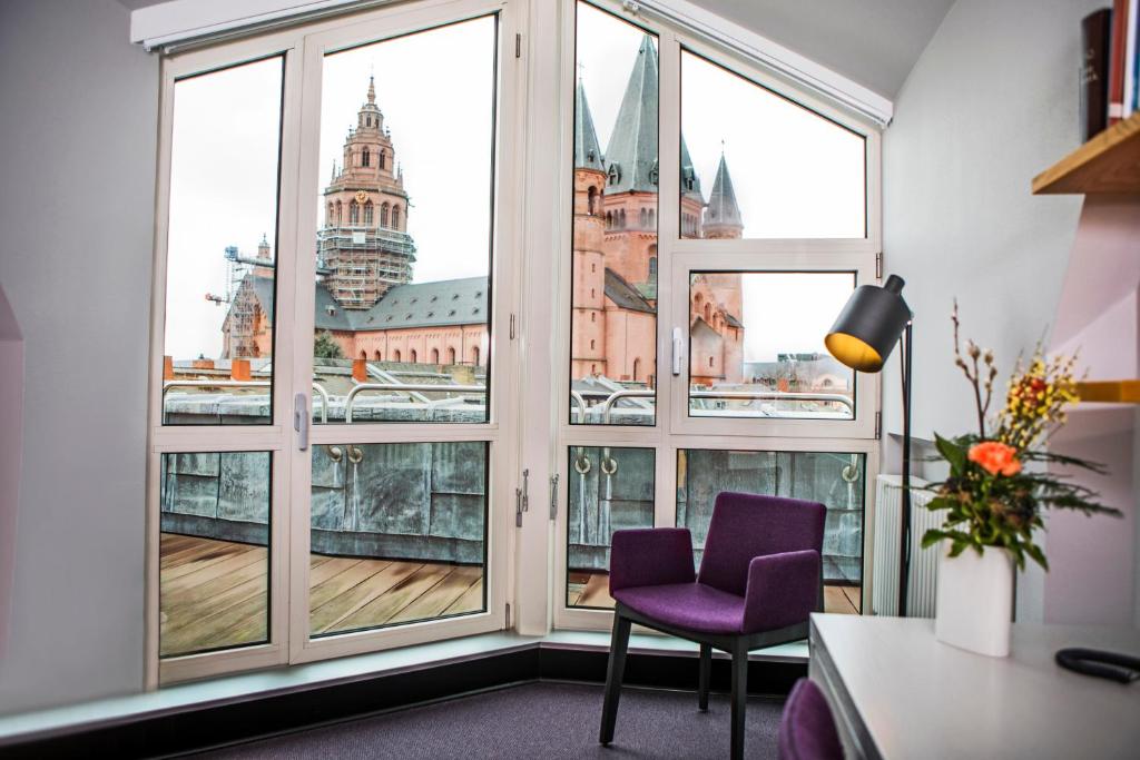 Zimmer mit einem Fenster mit einem lila Stuhl und Aussicht in der Unterkunft Erbacher Hof, Bistum Mainz in Mainz