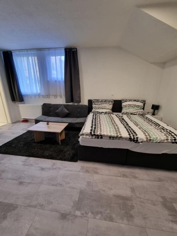 een slaapkamer met een bed, een bank en een tafel bij SM Apartment in Triberg