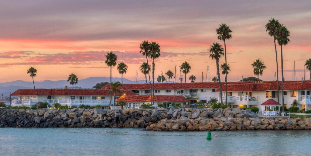 a view of a resort from the water with palm trees at Oceanside Marina Suites - A Waterfront Hotel in Oceanside