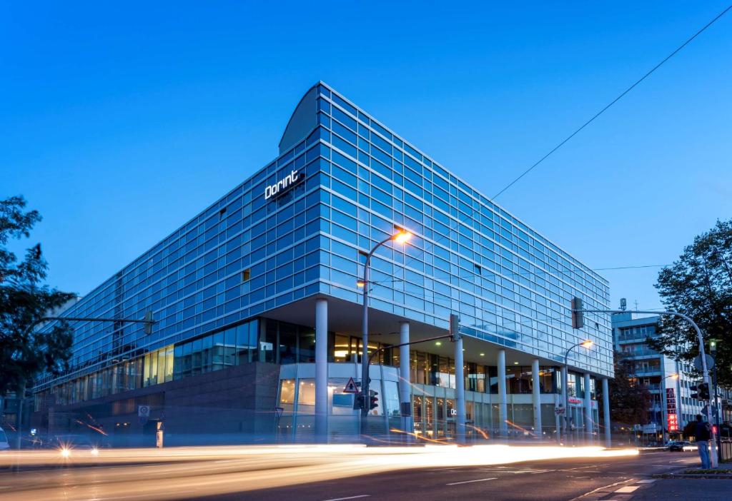 a large glass building on a city street at night at Dorint Kongresshotel Mannheim in Mannheim