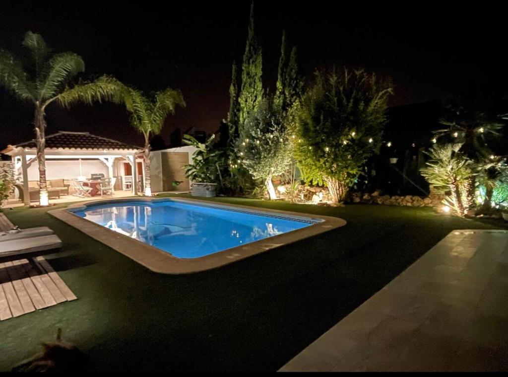 a swimming pool in the middle of a yard at night at 1 Habitación con baño privado frente a la piscina, máximo para 4 personas, No es la casa completa,1cama y 1 sofa-cama in San Vicente del Raspeig