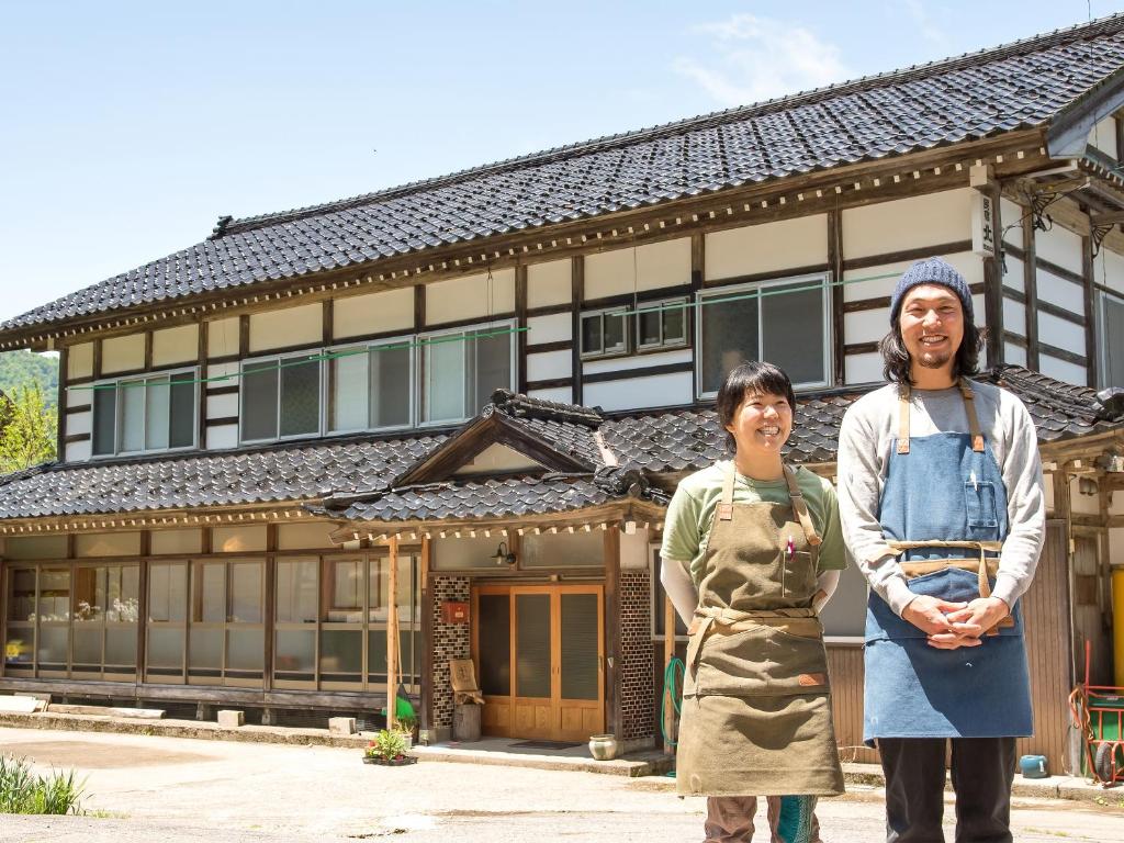 deux femmes debout devant un bâtiment dans l'établissement Guest House Takazuri-KITA, à Nanto