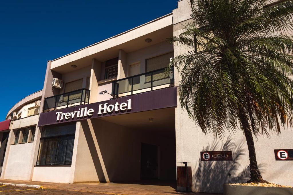 a hotel with a palm tree in front of it at Treville Hotel in Caràzinho