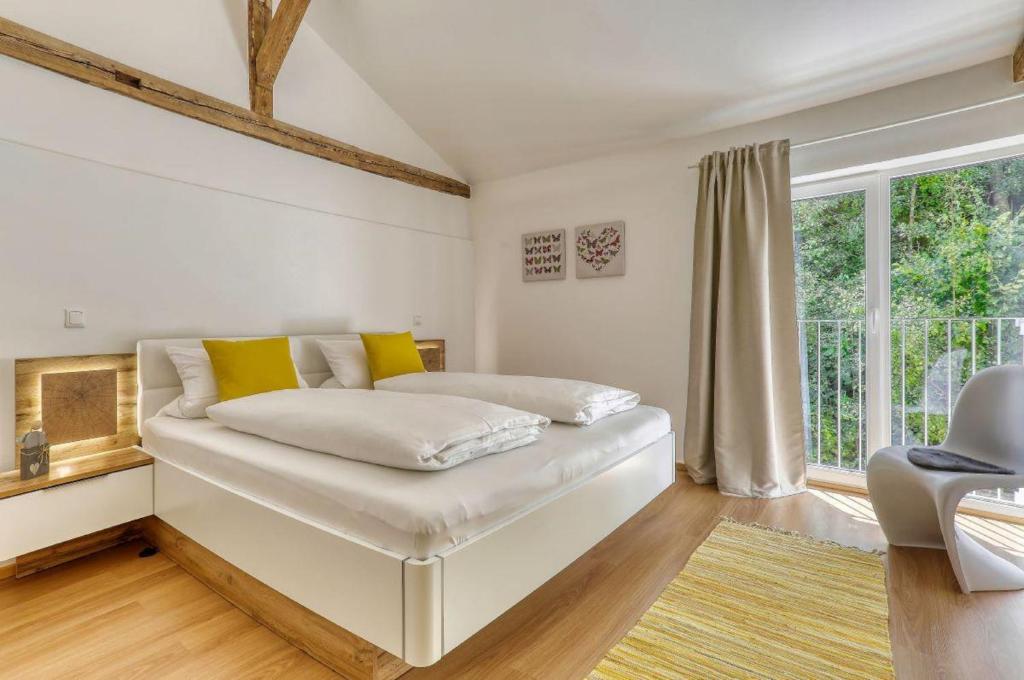 1 dormitorio con cama blanca y almohadas amarillas en Das Bachhaus, en Drachselsried
