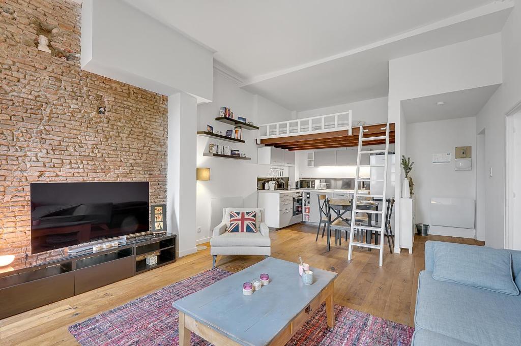 a living room with a blue couch and a brick wall at LE CODRUS - Charmant appartement dans l'hyper centre toulousain in Toulouse