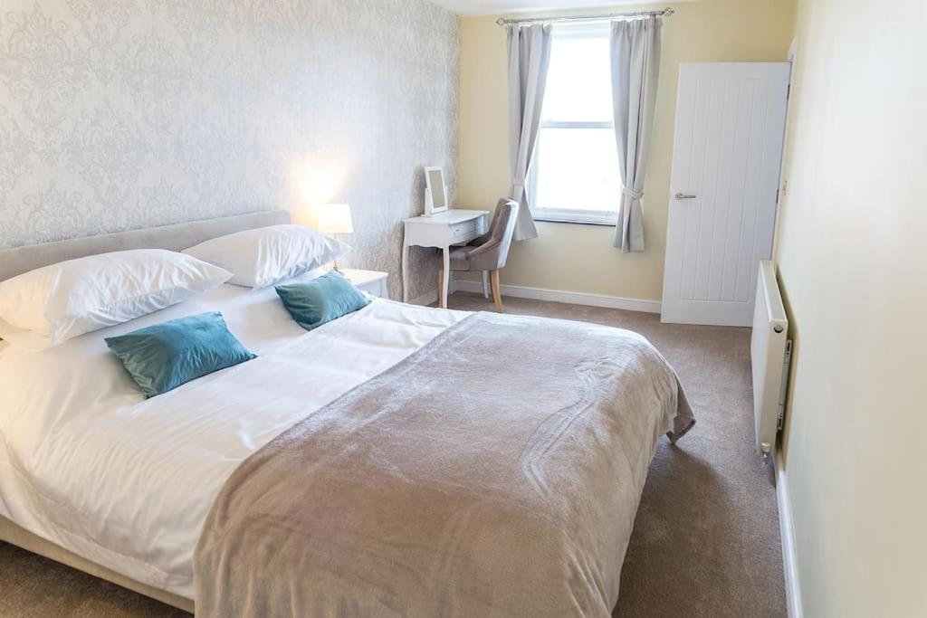 sypialnia z dużym białym łóżkiem z niebieskimi poduszkami w obiekcie Cosy, Boutique Central Kirkby Lonsdale Apartment w mieście Kirkby Lonsdale