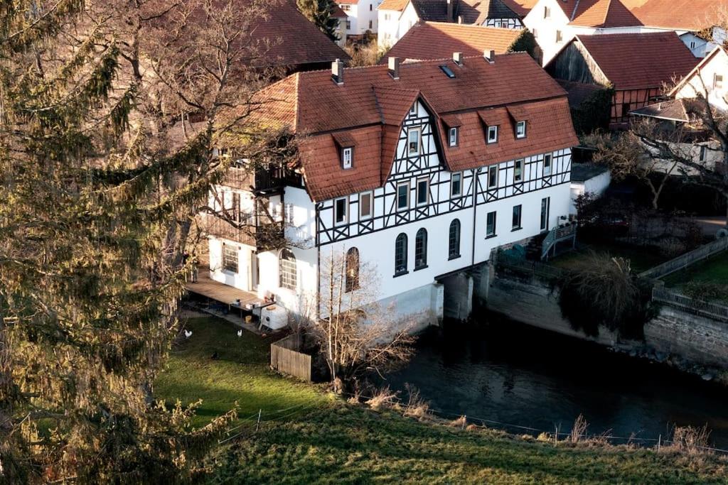 un grand bâtiment blanc à côté d'une rivière dans l'établissement Ferienwohnung Maris, à Burghaun