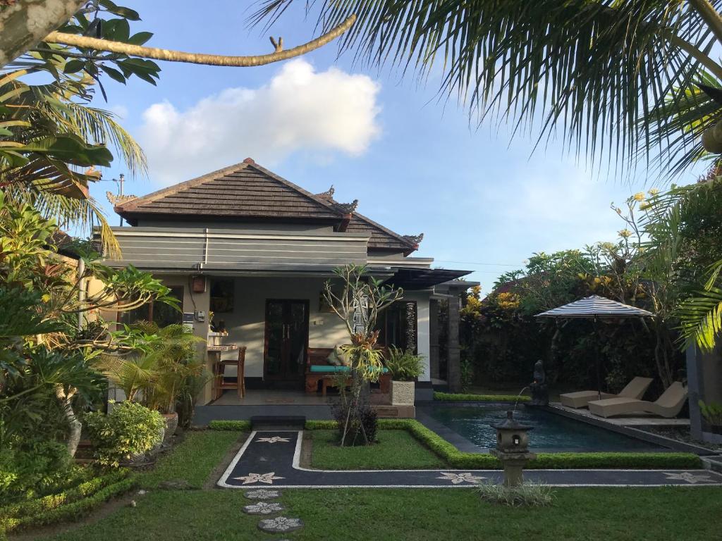 a villa with a swimming pool in a garden at Pondok Sawah Asri in Ubud