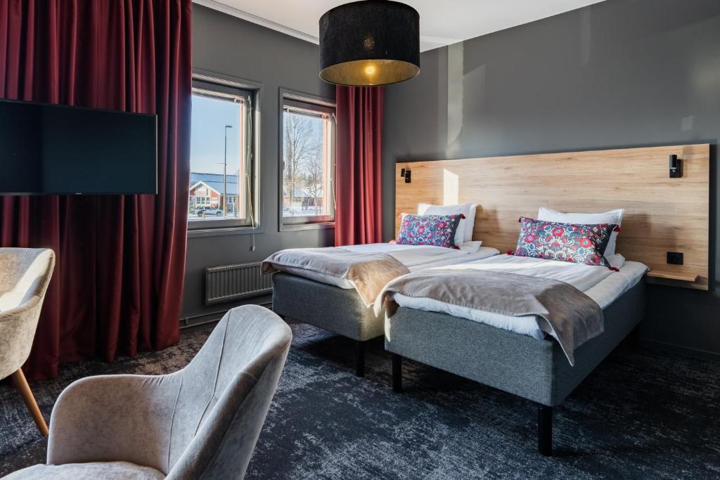 a hotel room with two beds and a chair at Hotell Fridhemsgatan in Mora