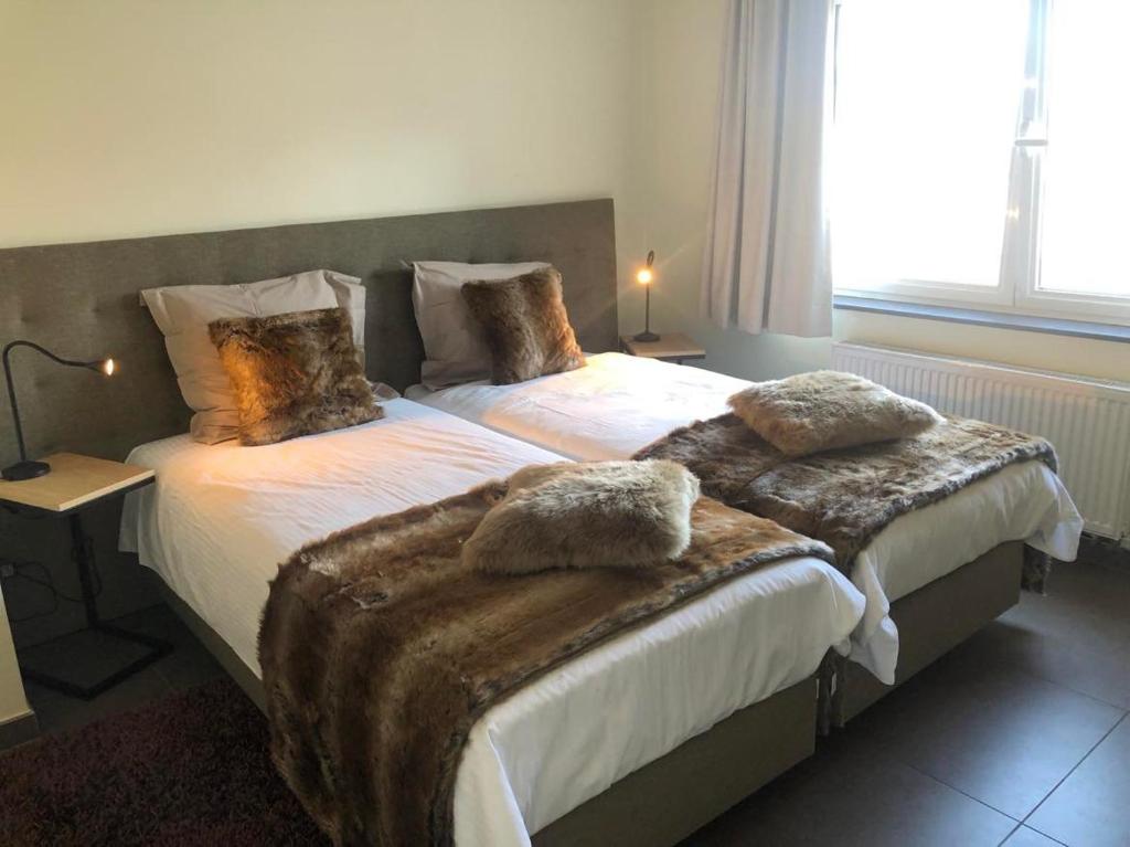 a bedroom with two beds with furry pillows on them at Logies Dampoort in Ghent